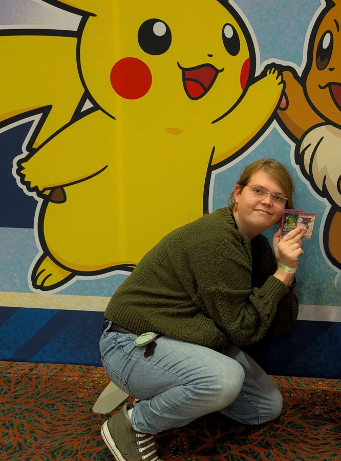 Reese smiling in front of colorful plush art at a local market